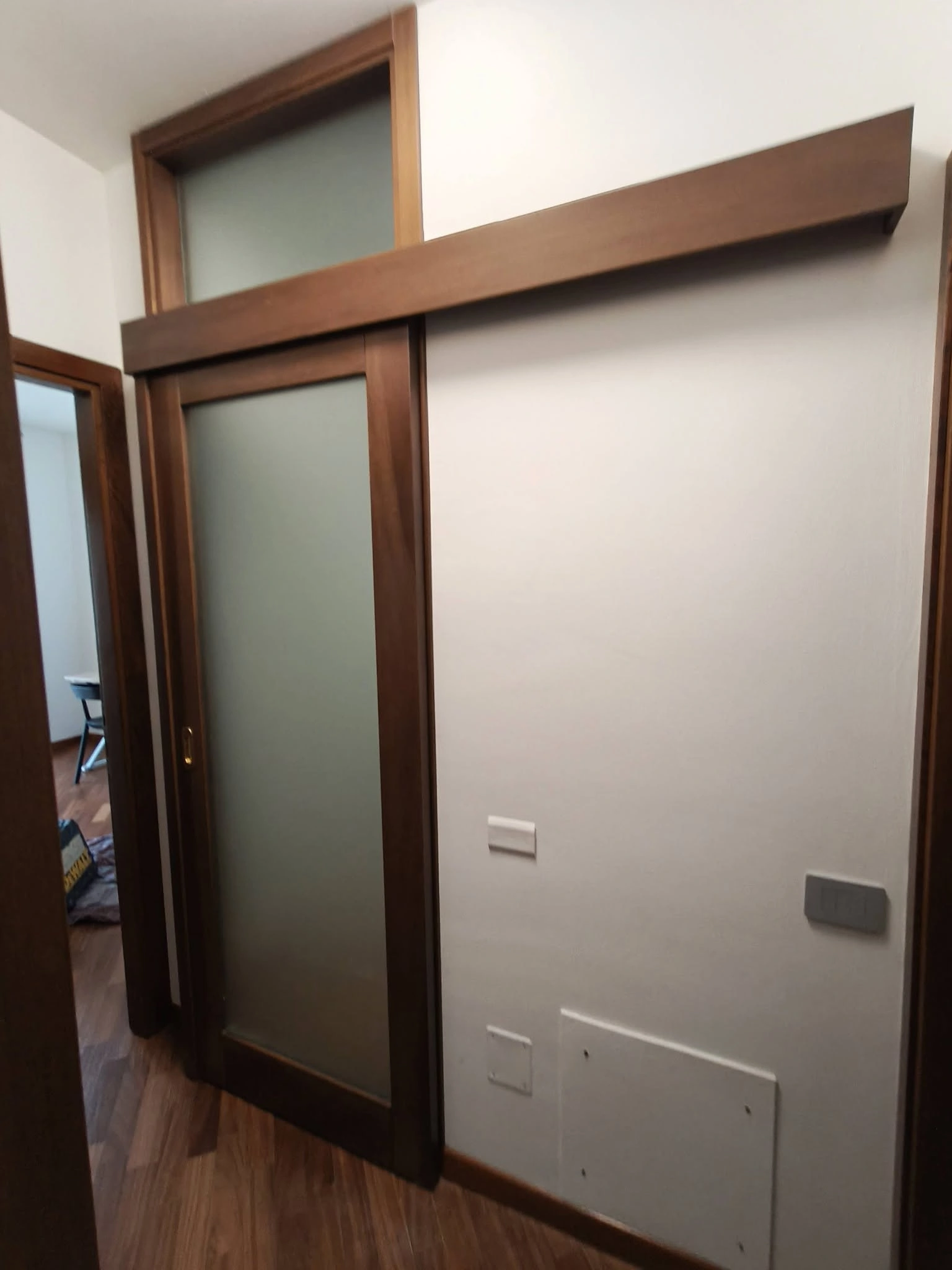 Porta scorrevole in legno con vetro satinato per chiusura vano scala.